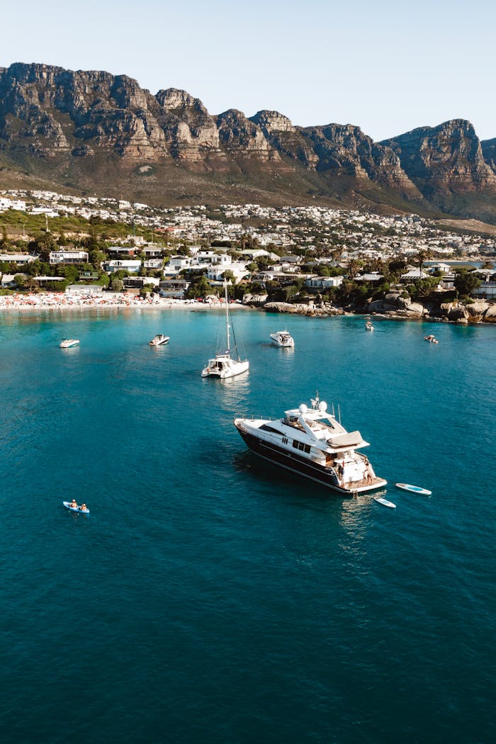 Stunning aerial view of a luxury yacht in Camps Bay, Cape Town with mountain backdrop.